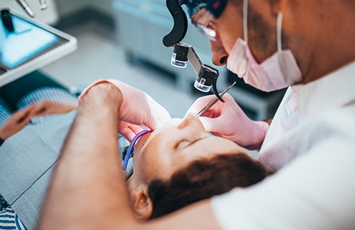 Dentist performing root canal on patient with dark hair