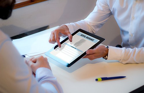 Two people zooming in on Dental Insurance on an electronic tablet