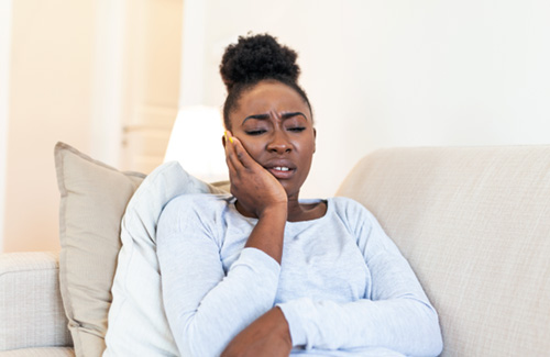 Woman with toothache sitting on couch