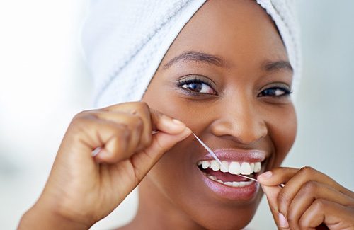 Woman smiling while flossing her teeth