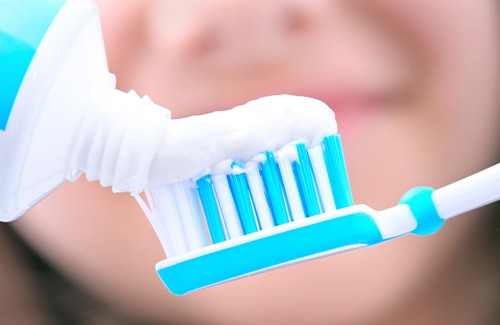 closeup of person putting toothpaste on toothbrush