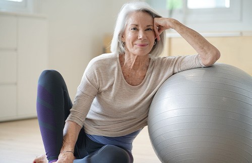 Woman smiling while leaning on yoga ball