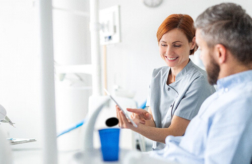 dental assistant smiling while showing patient image on tablet