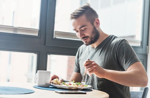 Man sitting at table by window eating lunch